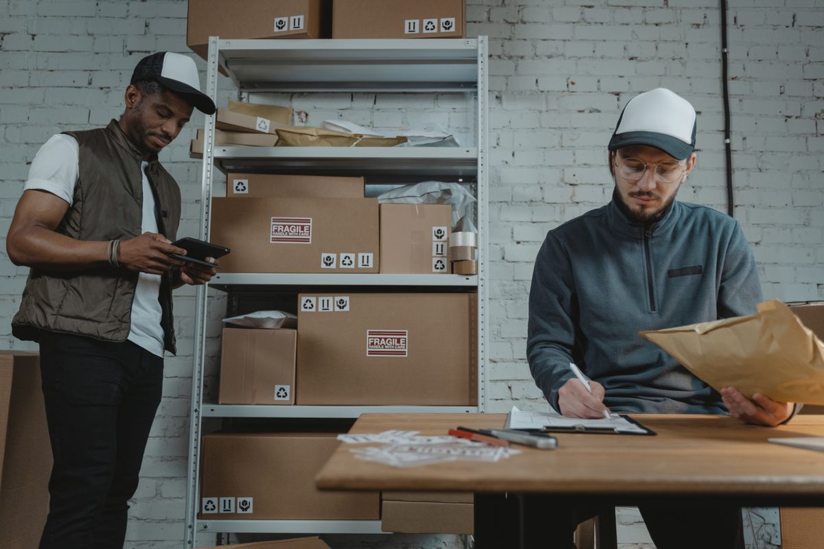 Dos personas preparando despachos entre cajas y papeles